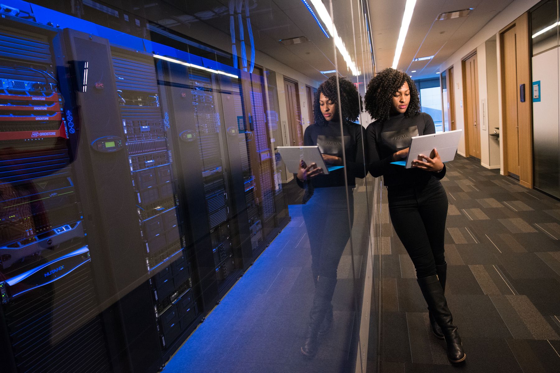 A technology professional reviewing a laptop beside server equipment.