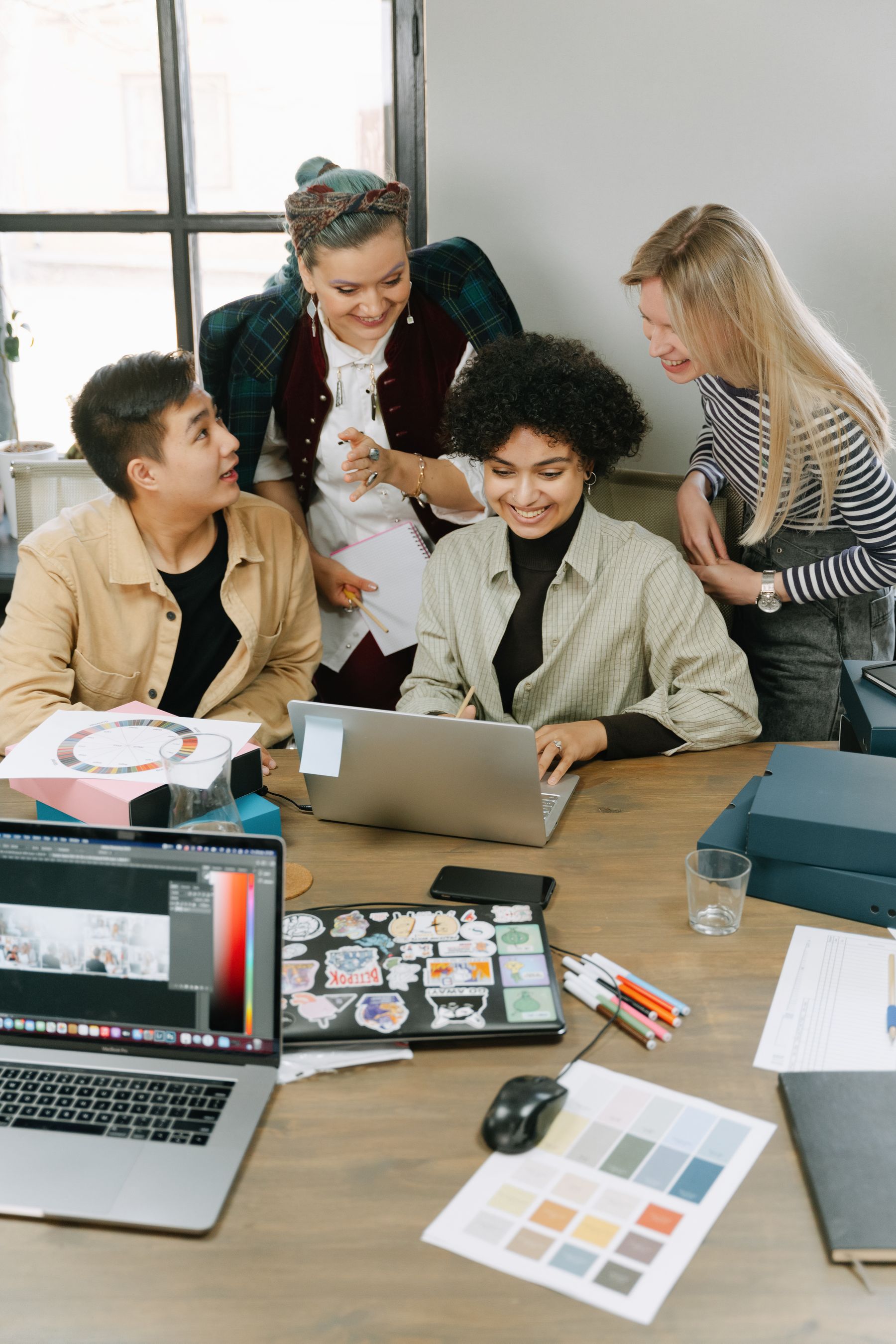 A creative team reviewing a laptop and design material together.
