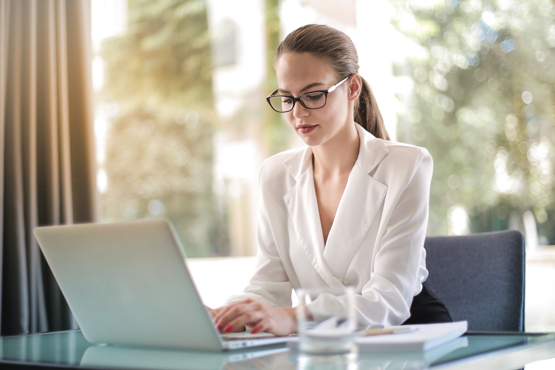 A professional working on a laptop beside a notebook.