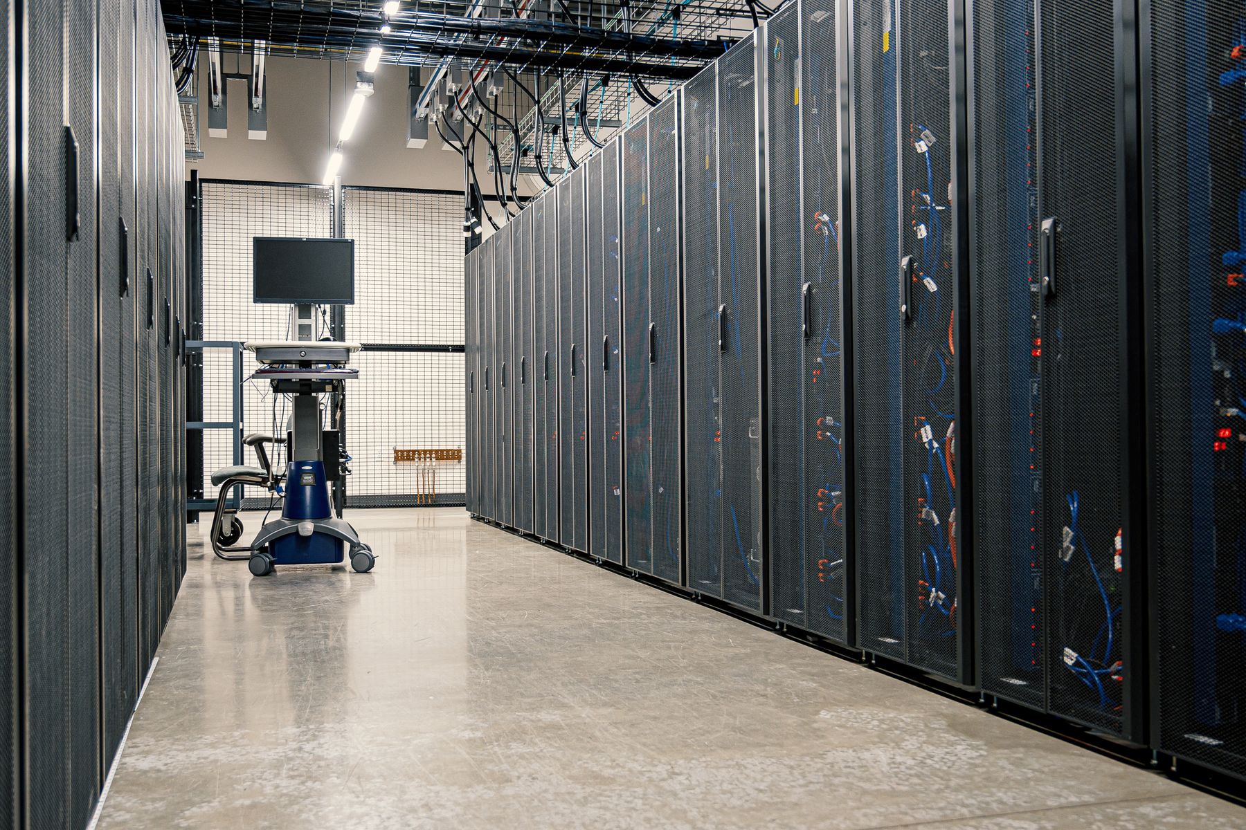 Rows of server cabinets with a maintenance workstation in a data centre.