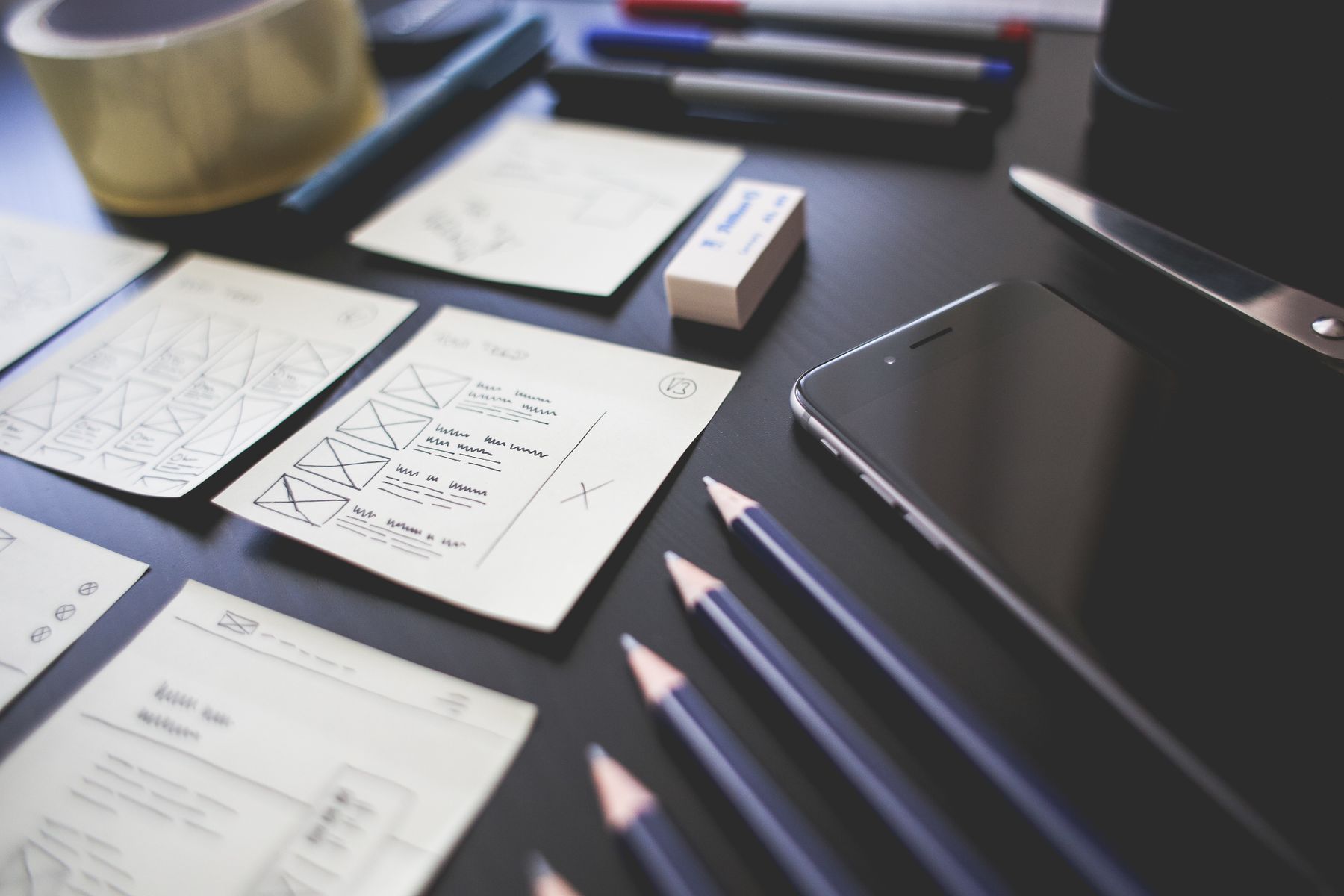 Website layout sketches, pencils and a phone on a planning desk.