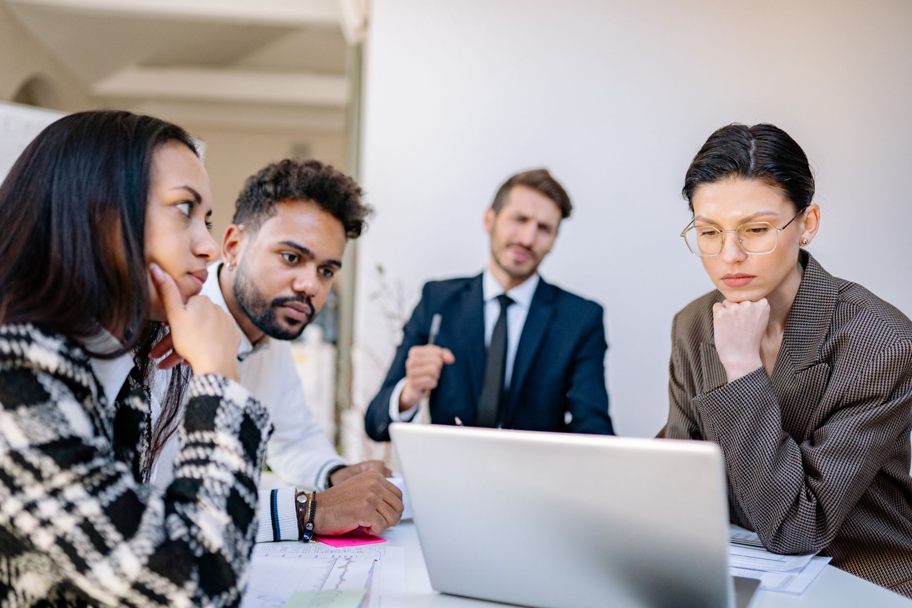 Four professionals reviewing information on a laptop together.