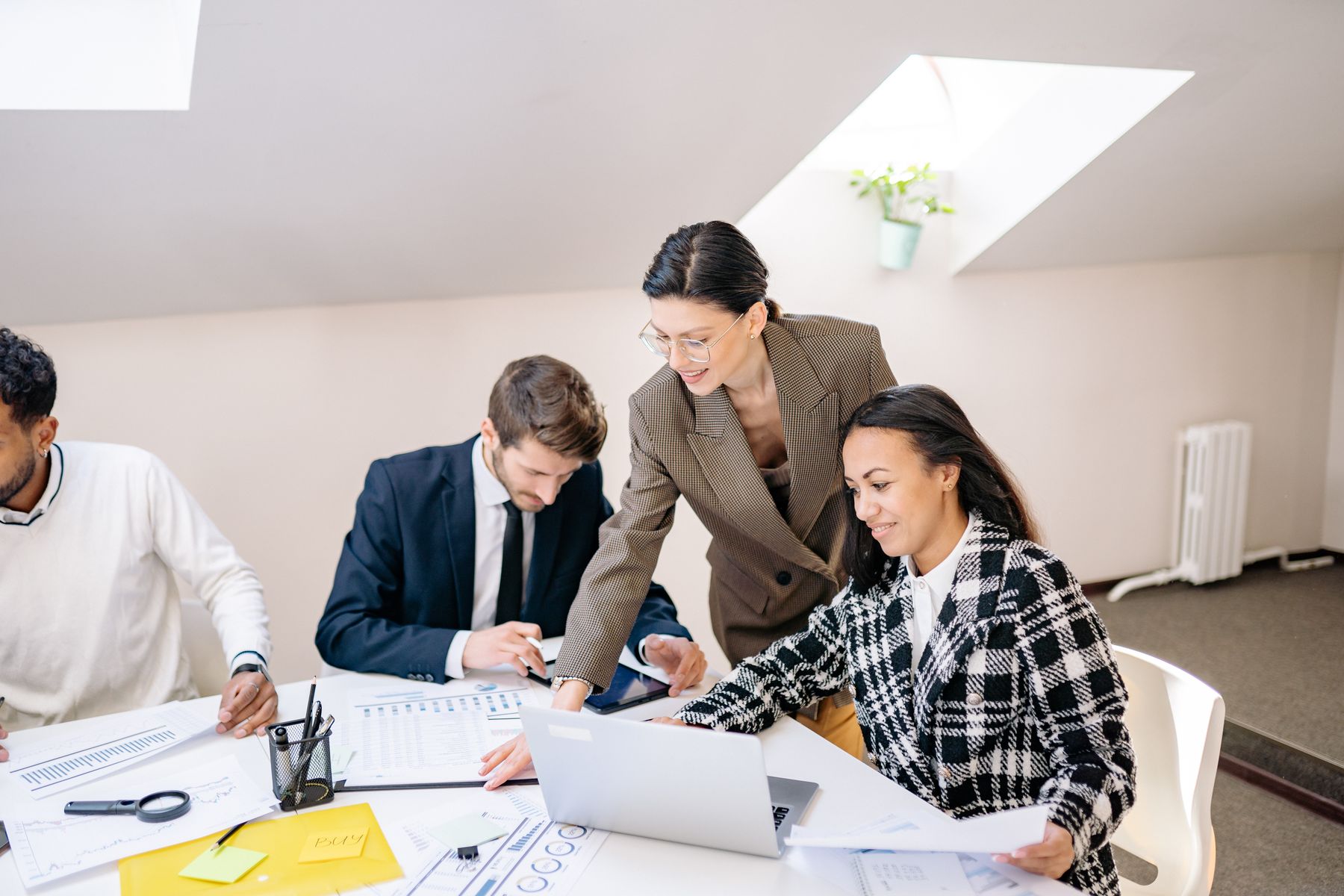 Professionals reviewing a laptop and printed questions together.