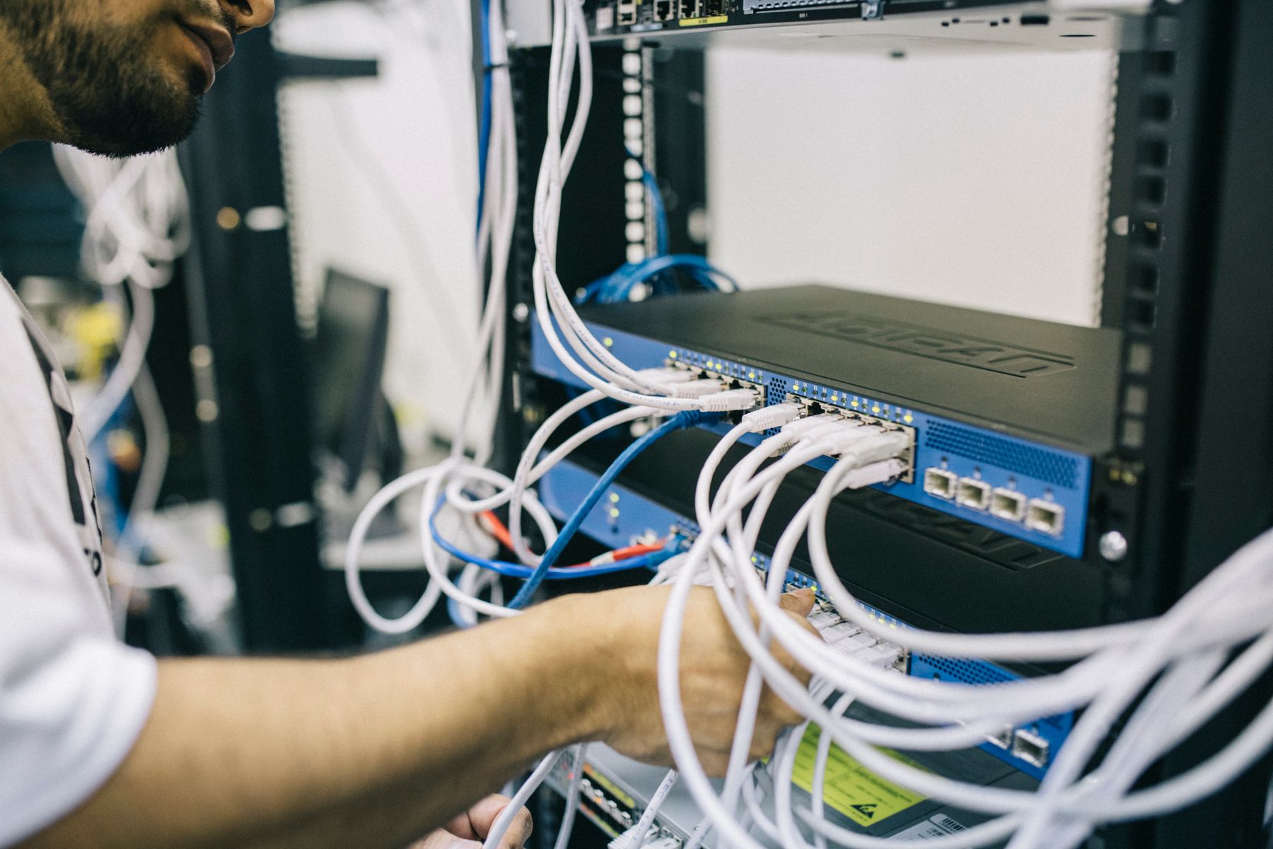 A technician checking cables connected to a network switch.
