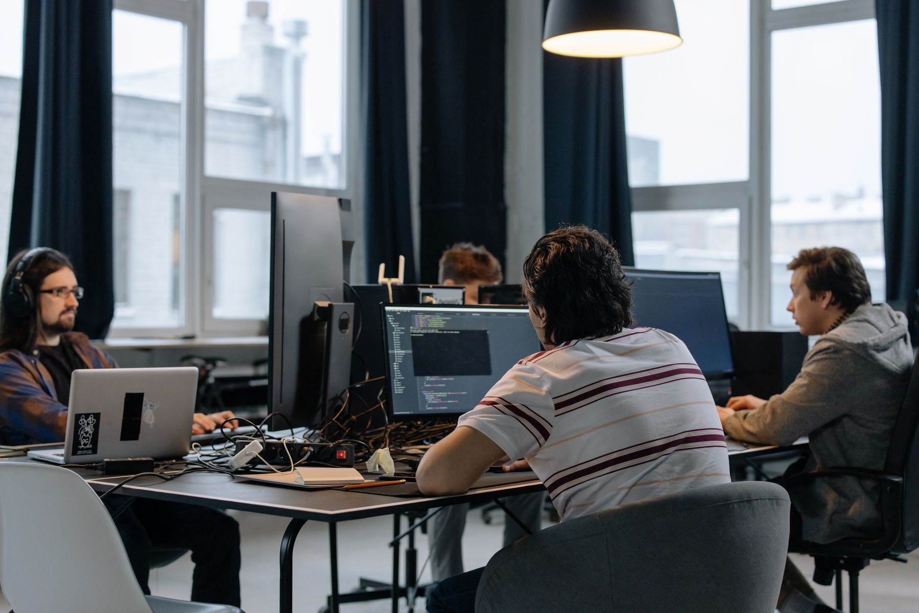 Developers collaborating at computer workstations in a bright office.