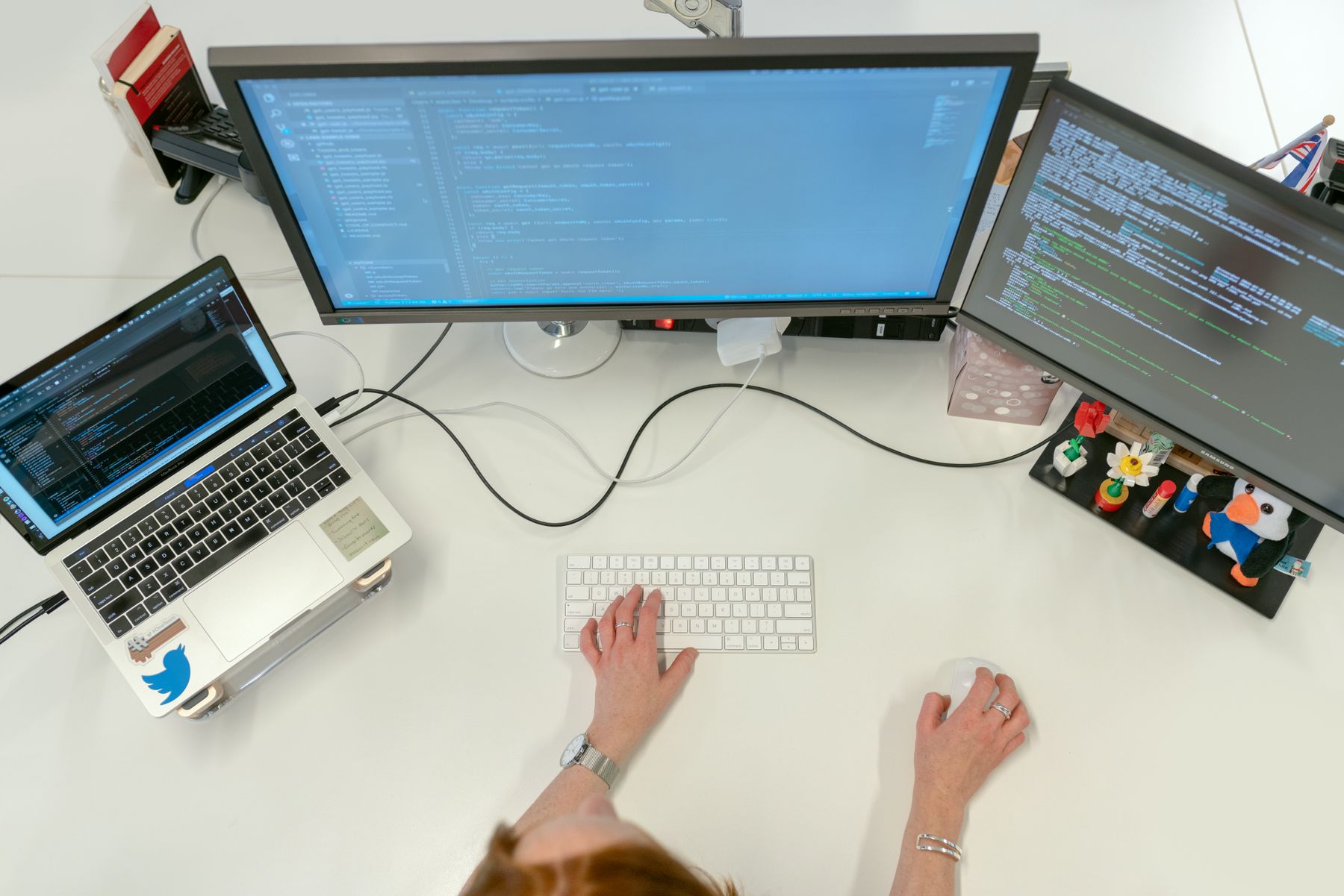 A developer working with code across a laptop and two monitors.