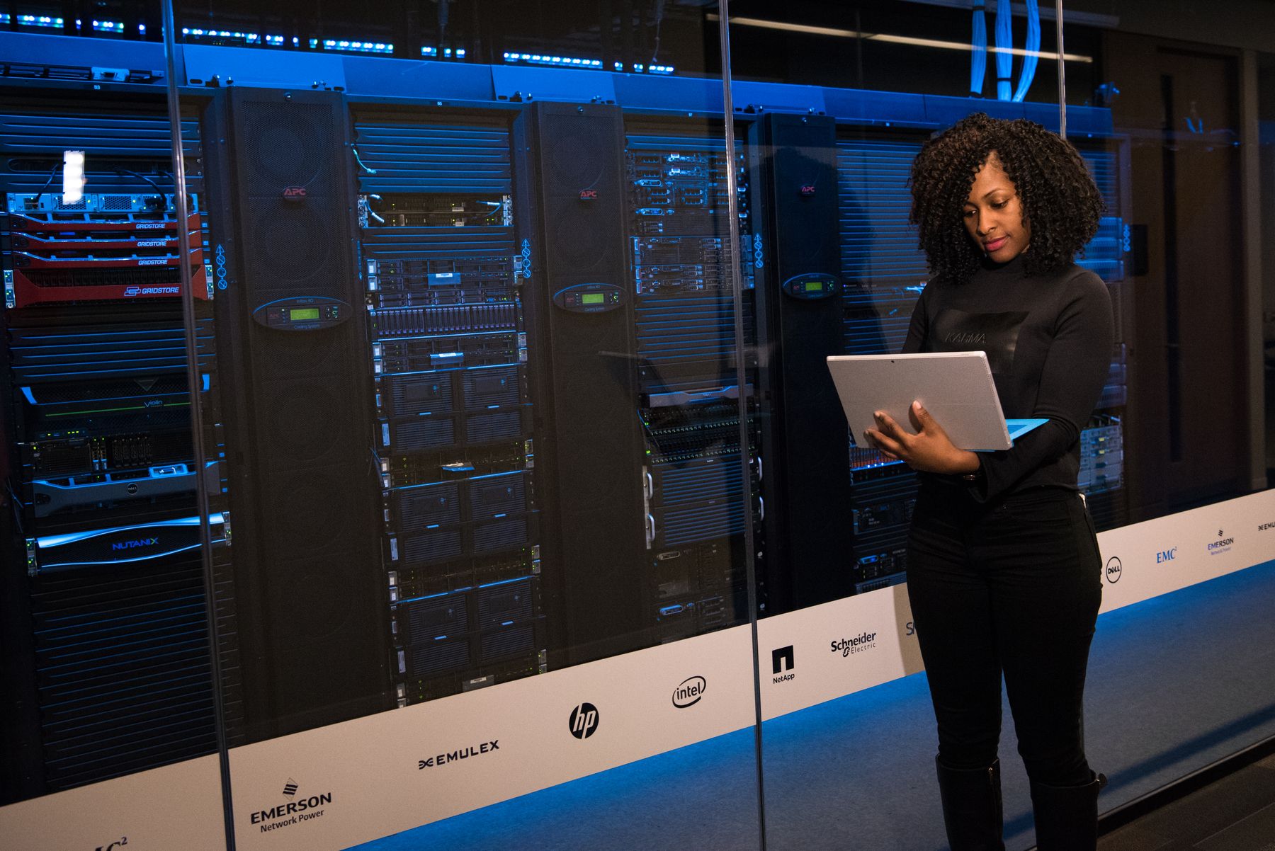 A technology professional reviewing a laptop beside server equipment.