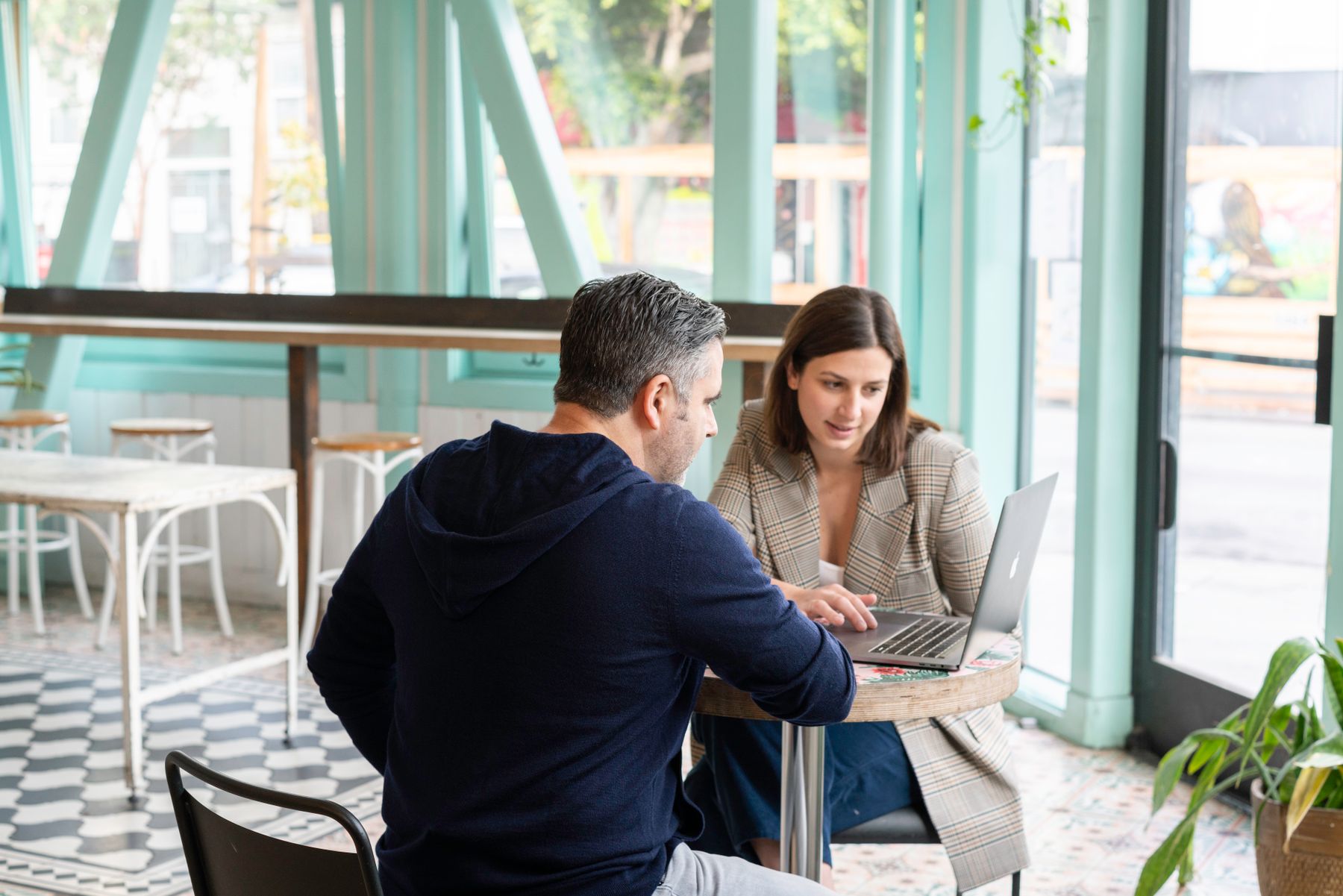 Two professionals discussing a laptop at a cafe table.