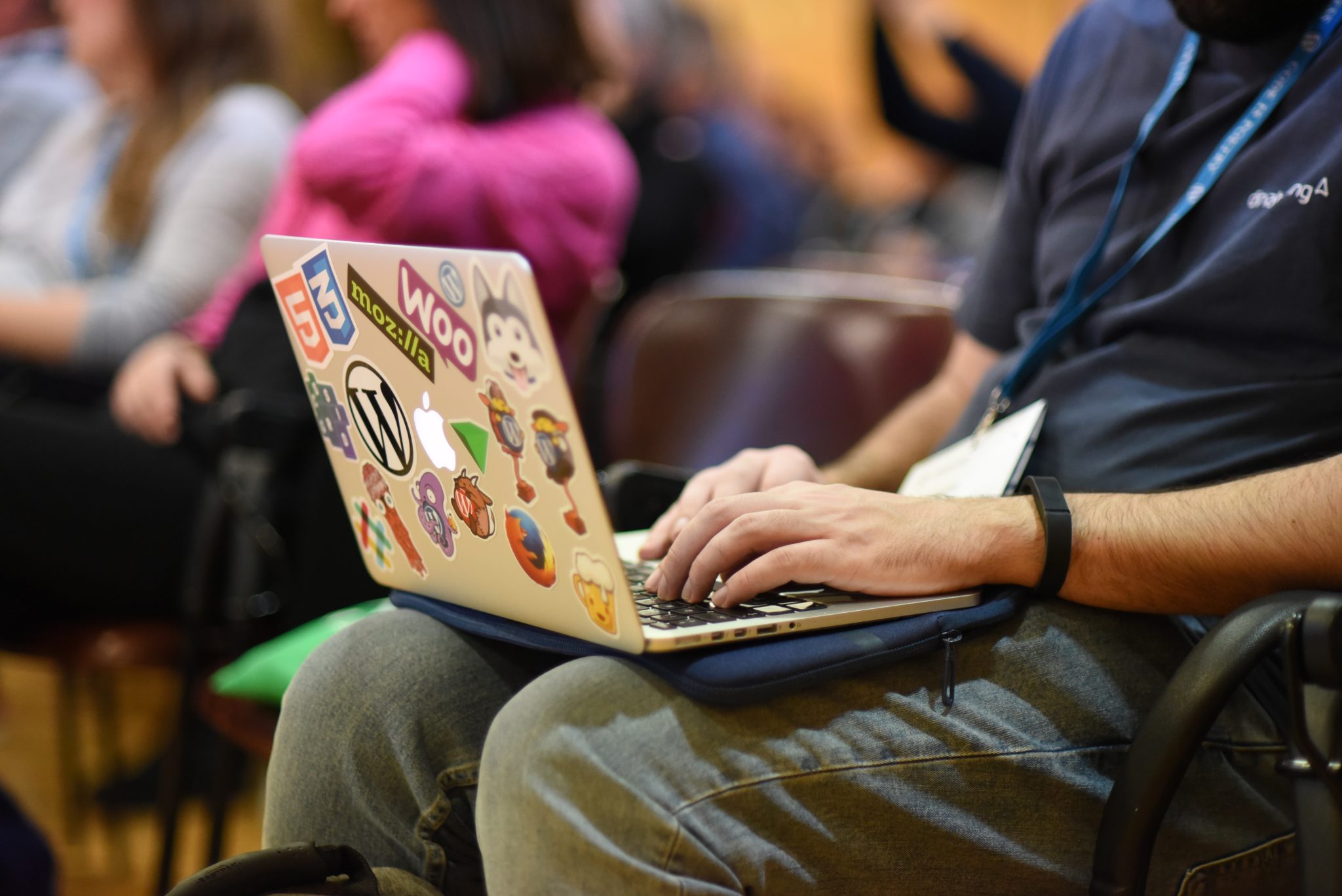 A WordCamp attendee using a laptop with WordPress and web-development stickers.